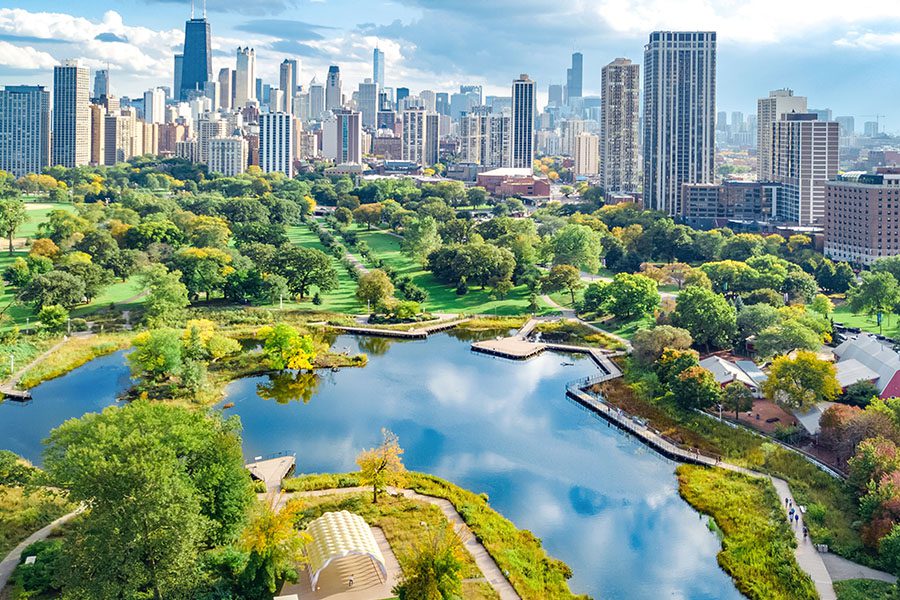 Contact - Aerial View of the Chicago Skyline Displaying Many Buildings and a Park With Many Trees and a Large Lake